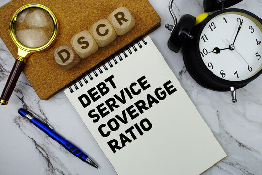 DSCR Debt Service Coverage Ratio text written on notepad with calculator and magnifying glass on marble background