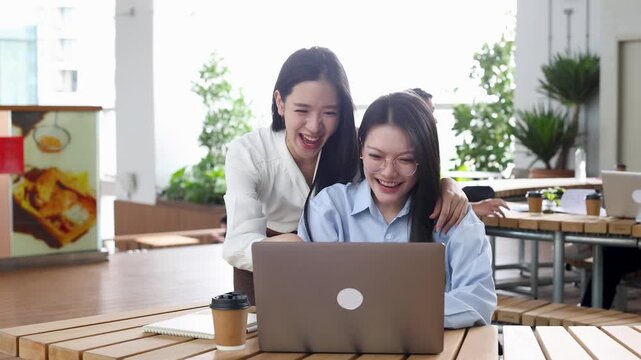 Two Asian Businesswomen High Five Celebrating Success in Modern Bangkok Office