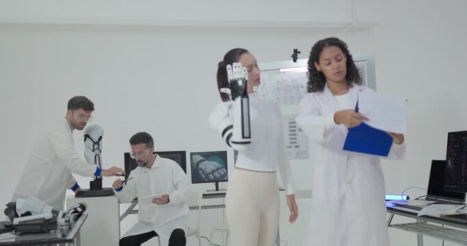 Engineers presenting and testing robotic arm at technical drawing board in white robotics lab