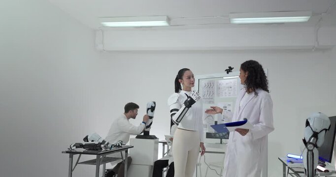 Engineers presenting and testing robotic arm at technical drawing board in white robotics lab