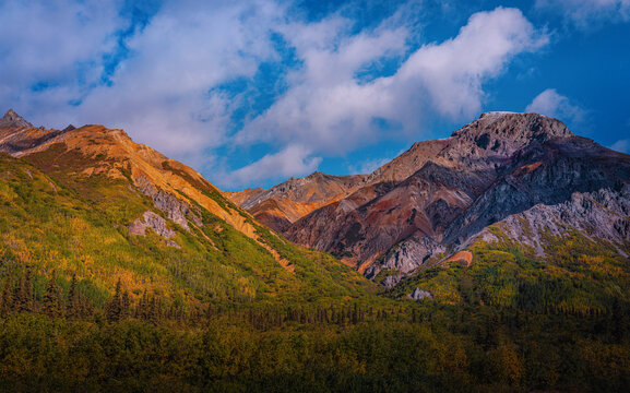 Sheep Mountain in the eastern Talkeetna Mountains along the Glenn Highway in Matanuska Glacier Alaska with vibrant red, orange and yellow volcanic mineral layers on the cliffs