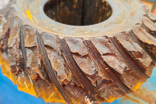 Spiral bevel gear of engine transmission in damaged and cracked condition due to heavy duty used. Industrial equipment object, close-up with selecive focus.