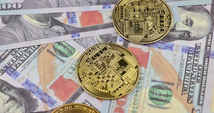 Horizontal detailed macro view of hand stacking shiny physical bitcoin coins vertically into a tower on top of spread US hundred dollar cash bills.