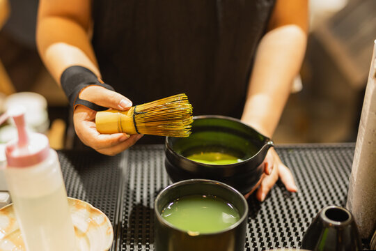 Barista holding a traditional bamboo whisk while preparing Japanese matcha.