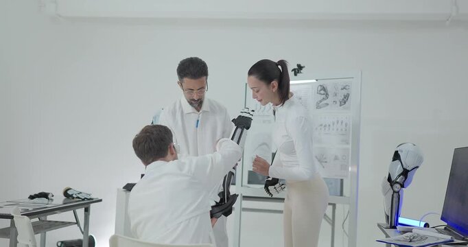 Engineers presenting and testing robotic arm at technical drawing board in white robotics lab