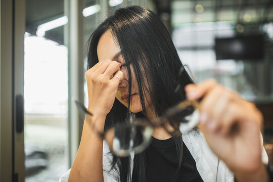 Woman experiencing blurred vision and eye strain while working on a laptop, illustrating tired eyes, visual fatigue, screen-related discomfort and digital eye health.