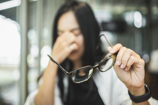 Woman experiencing blurred vision and eye strain while working on a laptop, illustrating tired eyes, visual fatigue, screen-related discomfort and digital eye health.