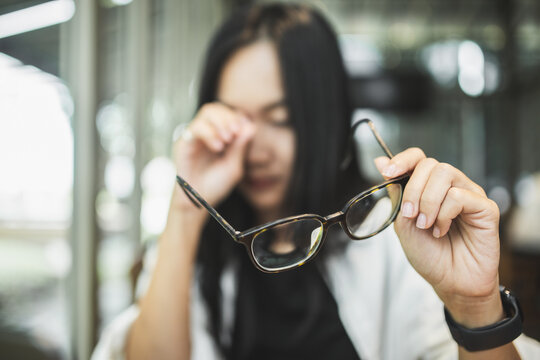 Woman experiencing blurred vision and eye strain while working on a laptop, illustrating tired eyes, visual fatigue, screen-related discomfort and digital eye health.