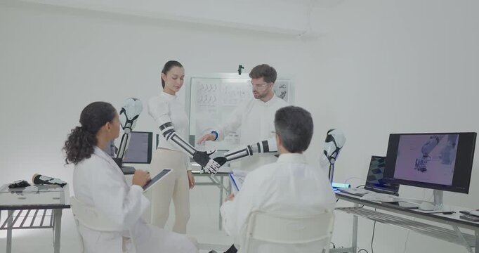 Engineers presenting and testing robotic arm at technical drawing board in white robotics lab