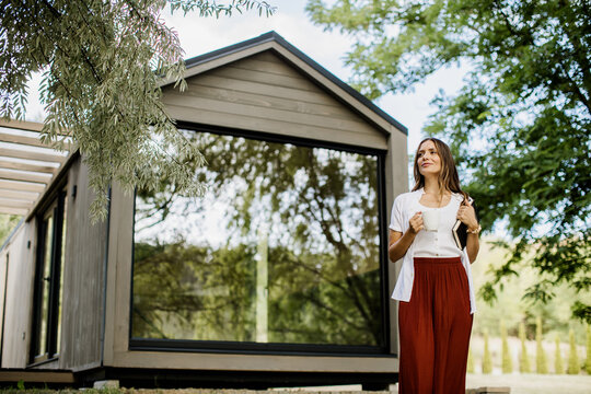 Charming moments of a woman enjoying nature by a modern cabin