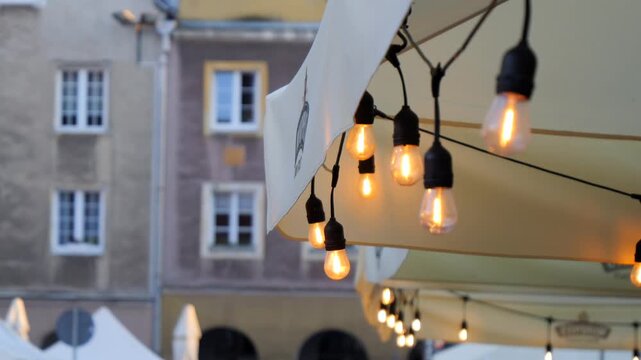 Warm decorative string lights glow outside a restaurant in a historic old town creating an inviting evening atmosphere