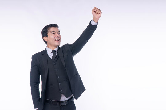 Successful businessman in black suit raising fist high in victory celebrating career breakthrough isolated on white background with copy space for text.