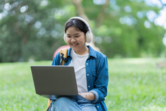 Student studying online with laptop and headphones outdoors