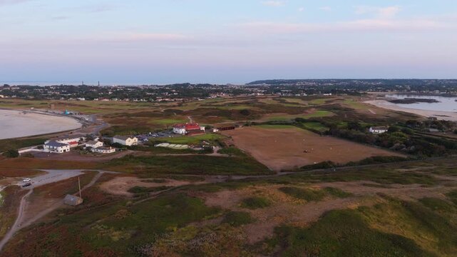 Lancresse Bay,Guernsey,Channel Islands.Golden hour high footage of Lancresse Bay panning over Lancresse Common,golf course and club houses to Chouet Beach and sky turning pink