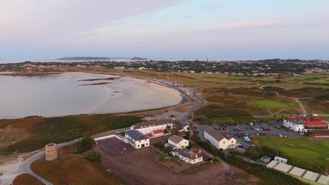 Lancresse Bay,Guernsey,Channel Islands.Golden hour high slow drone footage of all of Lancresse Bay , Lancresse Common,golf course,club houses and Herm,Jethou and Sark in the distance