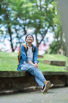 Asian student relaxing outdoors, enjoying peaceful college life