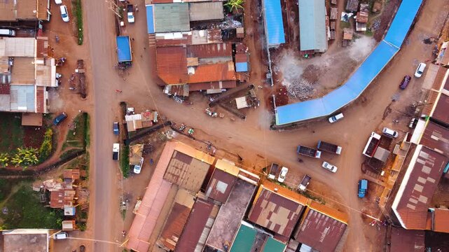 Top down aerial view of a rural commercial center in Embu, Kenya, showing intersecting roads, vehicles, market buildings and shops in a busy agricultural community.