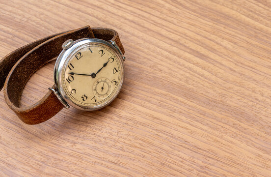 Vintage antique wristwatch with leather strap lying on wooden table. Retro timepiece with classic dial and copy space. Nostalgia, history and time concept. Accessory for collector and fashion backgrou