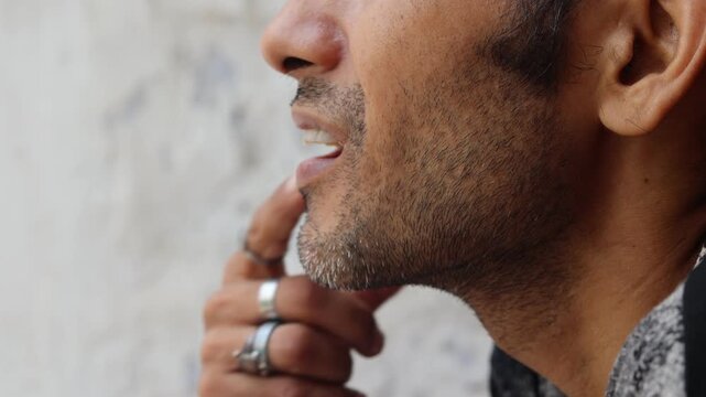  Close-up side profile of an Indian man resting his fingers near his lips while thinking deeply about life, personal struggles, stress, and important decisions.