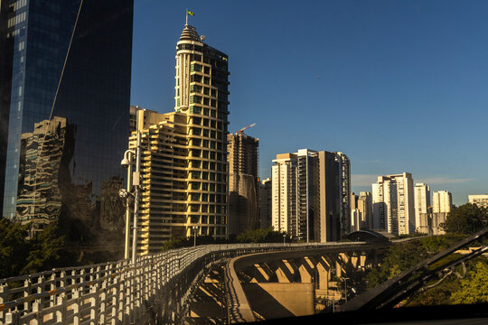 Panorama of modern corporate skyscrapers and concrete tracks from the front passenger window of an automated BYD SkyRail train operating on the driverless Monorail Line 17 Gold.