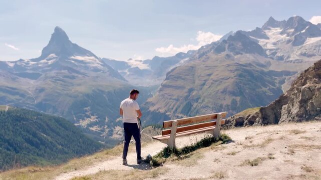 Man relaxing on a bench with views of the snow covered Matterhorn and Swiss Alps
