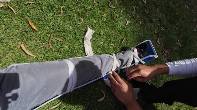 Emergency medical professional applying a splint to an injured person's leg during a first aid simulation