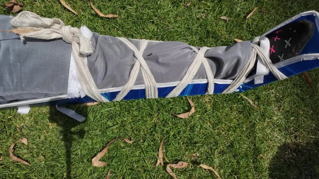 Paramedic student practicing immobilizing a fractured leg with a splint during a training exercise