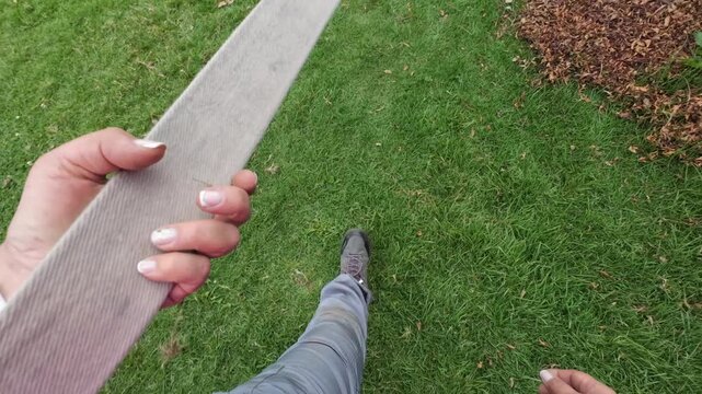 Pov of a person walking on green grass while holding a long slackline strap for setup