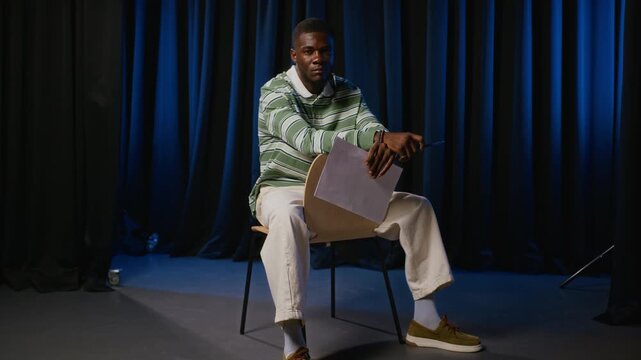 Portrait of young adult African American actor holding script during theater audition rehearsal. Clip suitable for drama school advertising, casting promos, or performing arts education