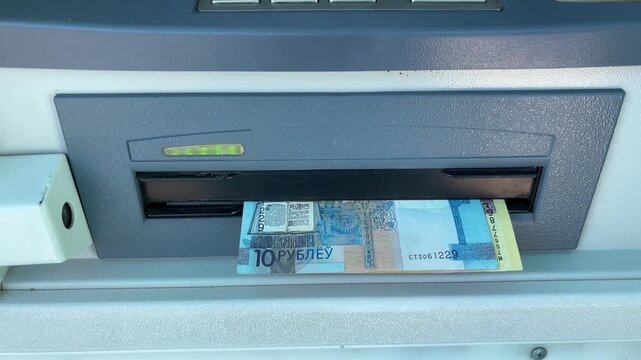 Cash banknotes coming out of an ATM dispenser, personal finance, banking, cash withdrawal, financial transaction.