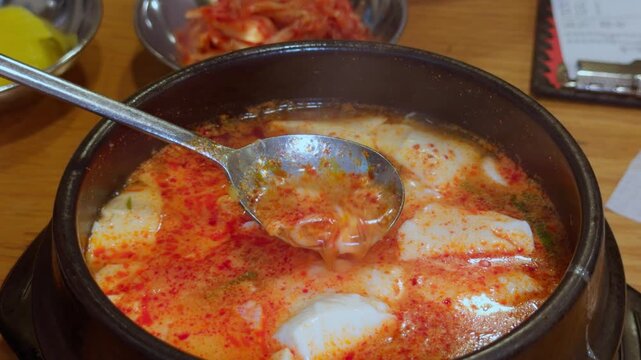 Korean Sundubu Jjigae Soft Tofu and Spicy Broth Lifted by Spoon Close-Up