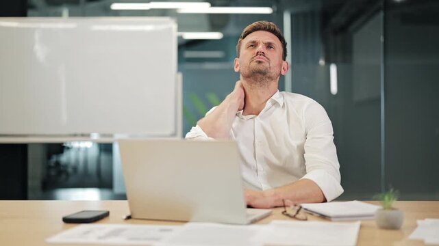 Business professional experiences significant neck pain while seated at workstation. Strain from prolonged computer use causes discomfort, requiring relief.