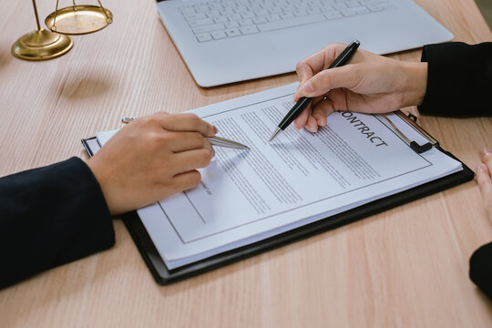 Business professionals reviewing and signing a contract document, representing legal agreements, corporate negotiations, business partnerships, and financial transactions.