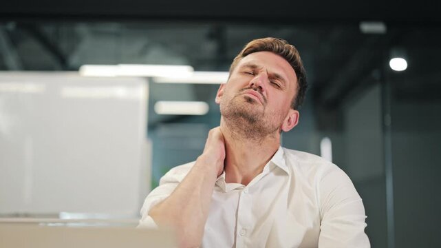 Office worker endures neck pain. Prolonged work causes discomfort. Stress and tension manifest physically, requiring massage and stretching. Workplace strain evident during busy day.