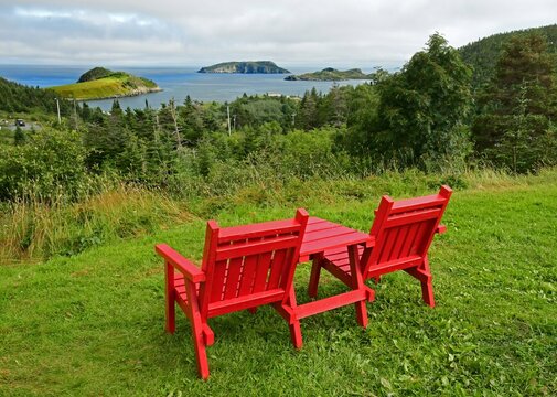 two red adirondack chairs in a scenic overlook in summer at tors cove , overlooking island and the north atlantic ocean along the irish loop on the avalon peninsula in newfoundland, canada
