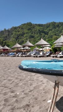 Old boat on tropical resort beach with sun loungers and thatched umbrellas