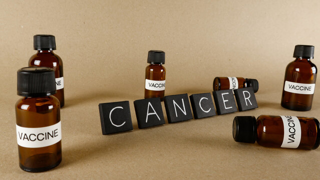 Vaccine vials and black letter blocks spelling CANCER represent medical research, healthcare, and the ongoing fight against disease, highlighting potential solutions