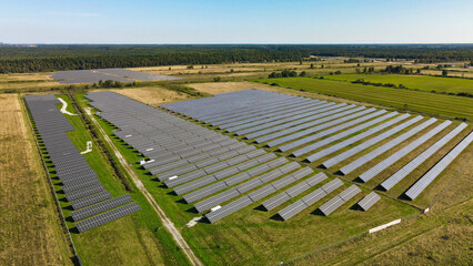Solar power station stands in a large green field and generates electricity, capturing renewable energy from the sun under a clear blue sky, promoting sustainability and ecological solutions © Dark Artistic
