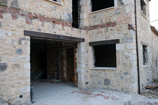 Stone house undergoing renovation with open windows