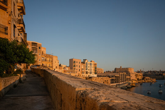 Stone wall viewpoint over a Maltese harbor at sunrise