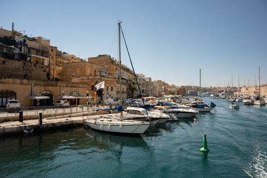 Sailboats and yachts docked at a sunny Maltese harbor