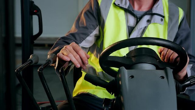 Close-up of forklift operator pulling a control lever downward while operating industrial lifting equipment during warehouse material handling.