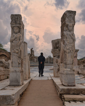 A man walking through the historic Heracles Gate with relief pillars on Curetes Street in the ancient city of Ephesus, Selcuk, Izmir, Turkey