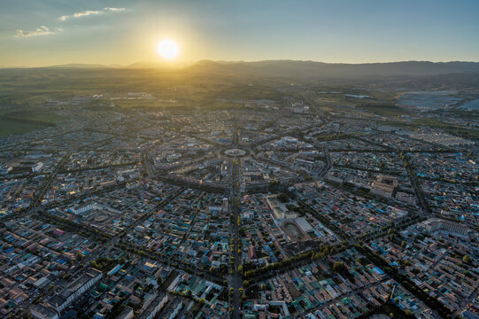 High-Angle Aerial Panoramic View of Tekes Bagua City at Golden Sunset, Ili Unique Bagua I-Ching Geometric Layout, Warm Twilight, Mountain Range and Horizon in Xinjiang