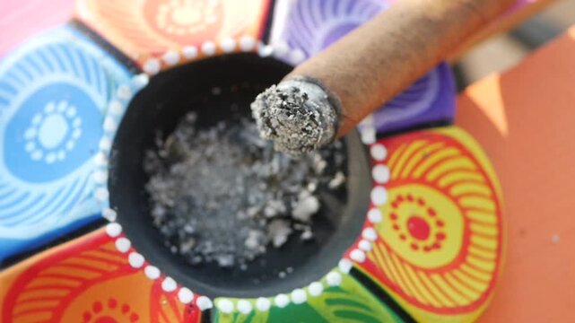 Burning cigar in an ashtray with colorful design