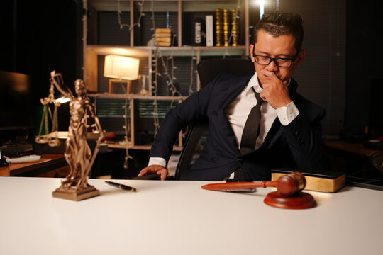 Pensive lawyer thinking about case strategy at office desk late night