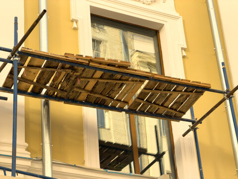 Scaffolding supports wooden planks above a window
