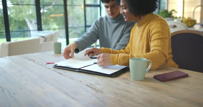 Handling black portfolio, African American men leaning, turning pages, reviewing papers at table
