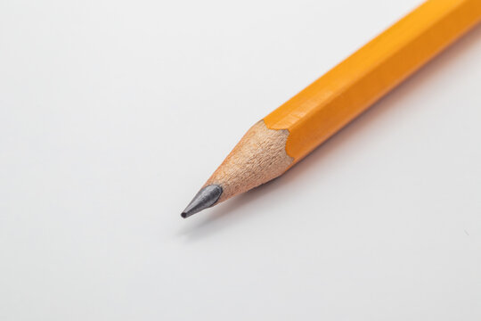 Close-up macro of sharp yellow graphite pencil tip isolated on white background with copy space
