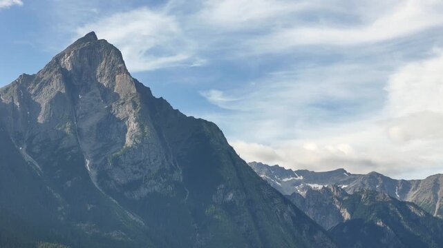 Aerial shot of a majestic mountain peak at New Hazelton, partly cloudy sky, expansive and serene.